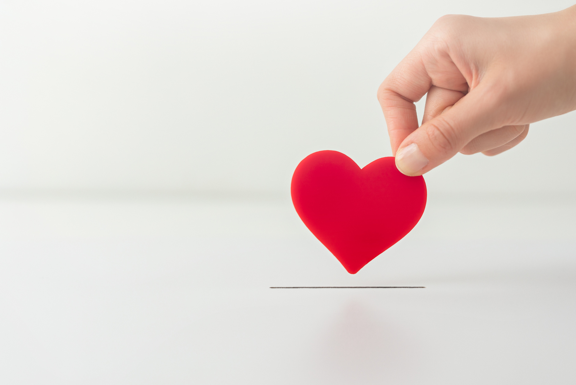 Hand Holding Heart Donating it for Charity on White Background